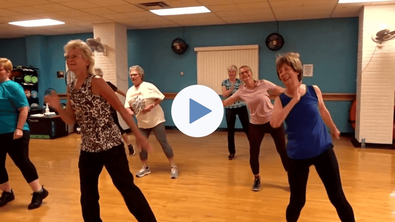 A group of older women dancing in a Zumba class in a community fitness room