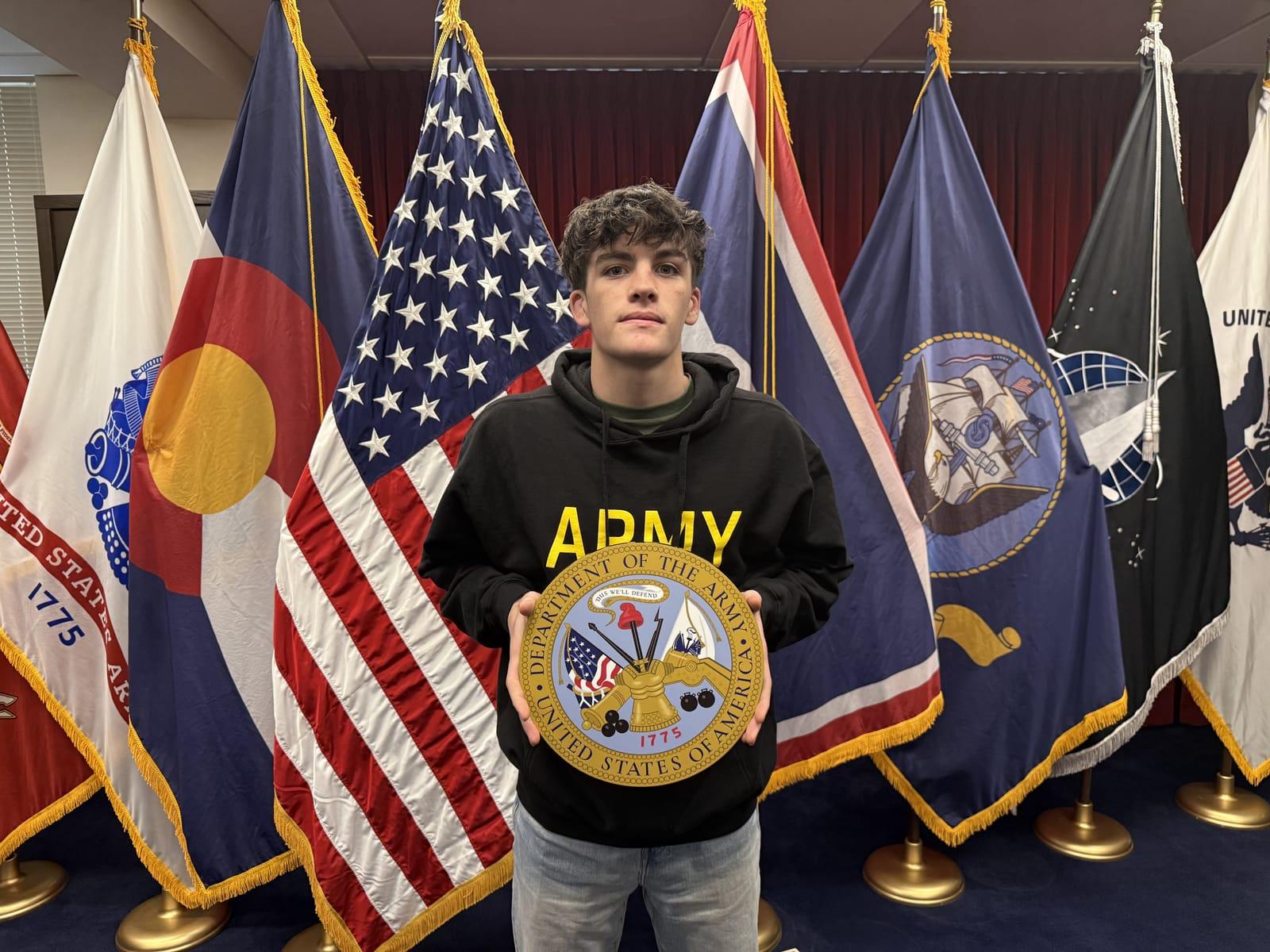 Kristen's son holding a Department of the Army seal in front of a row of military and state flags