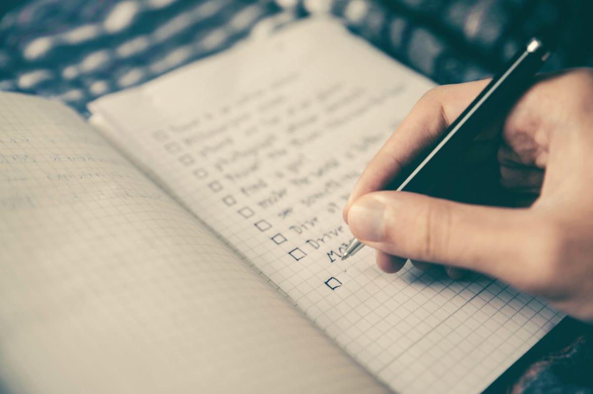 Hand checking off a personalized goal list in a notebook