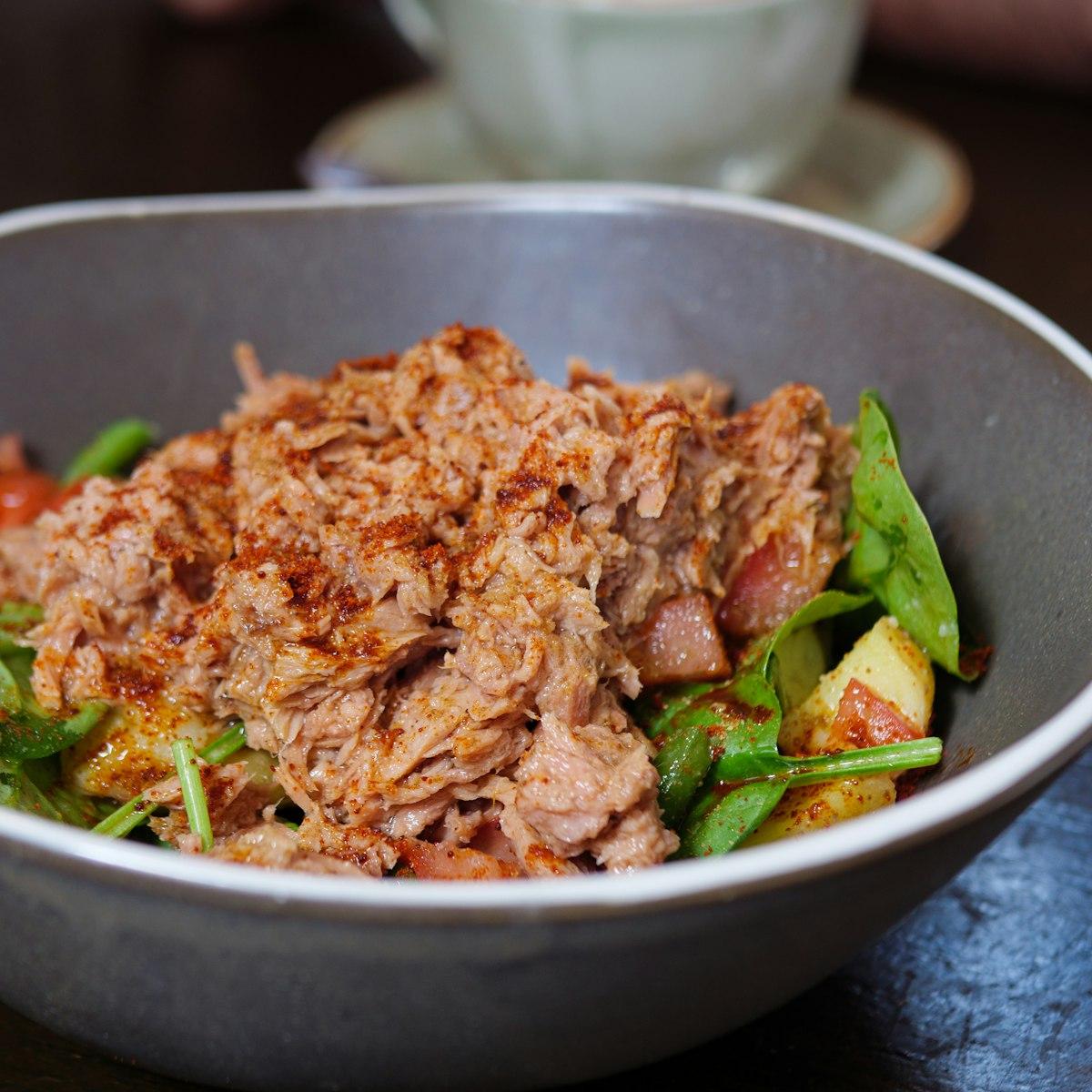 A bowl of flaked tuna salad over fresh greens