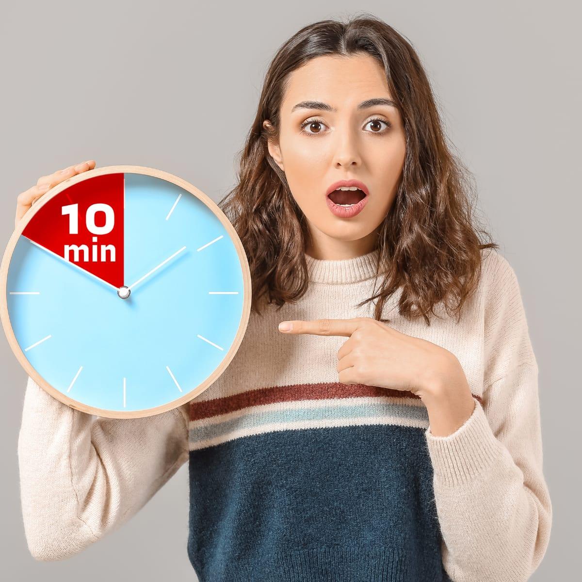A surprised woman pointing at a wall clock with a 10-minute section highlighted in red