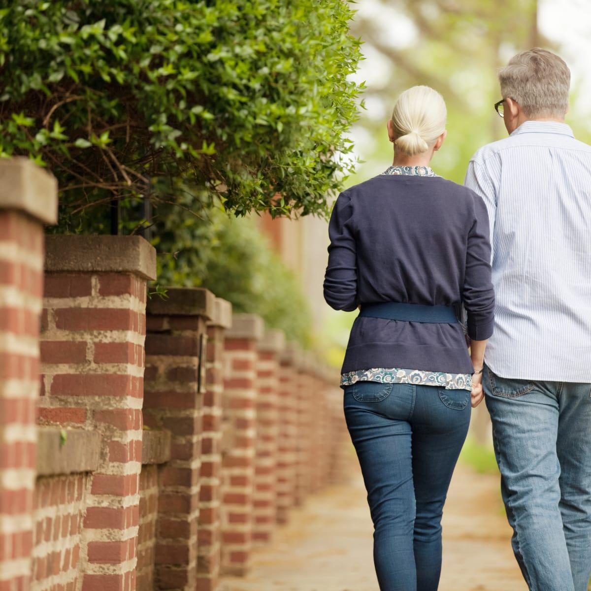 An older couple taking a walk together along a brick wall