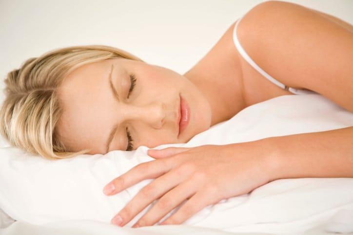 A woman sleeping peacefully on a white pillow