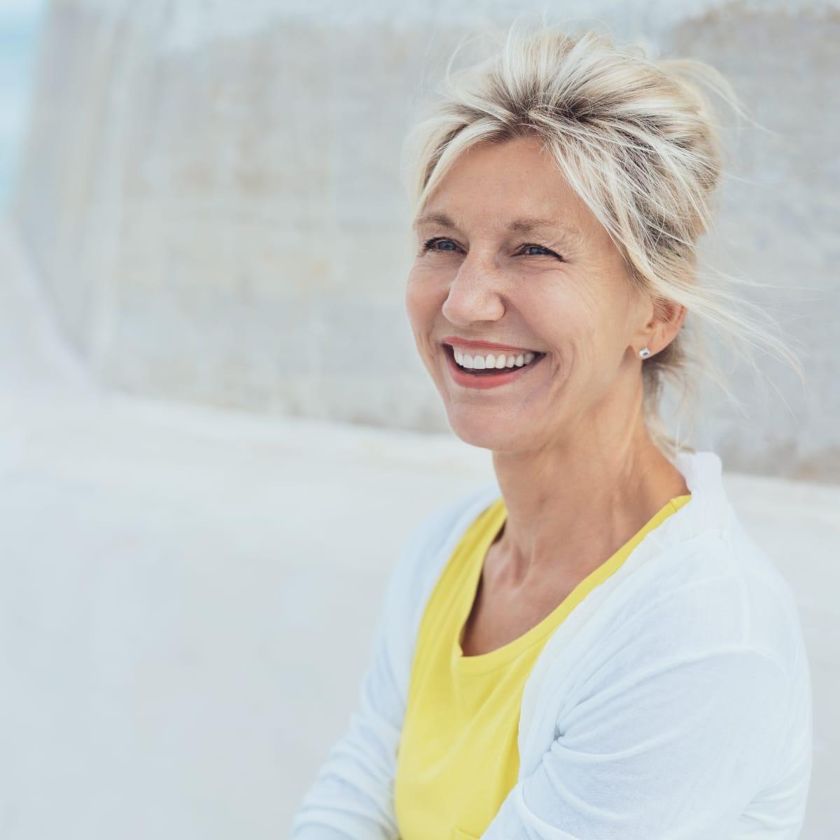 A smiling older woman in a white cardigan outdoors