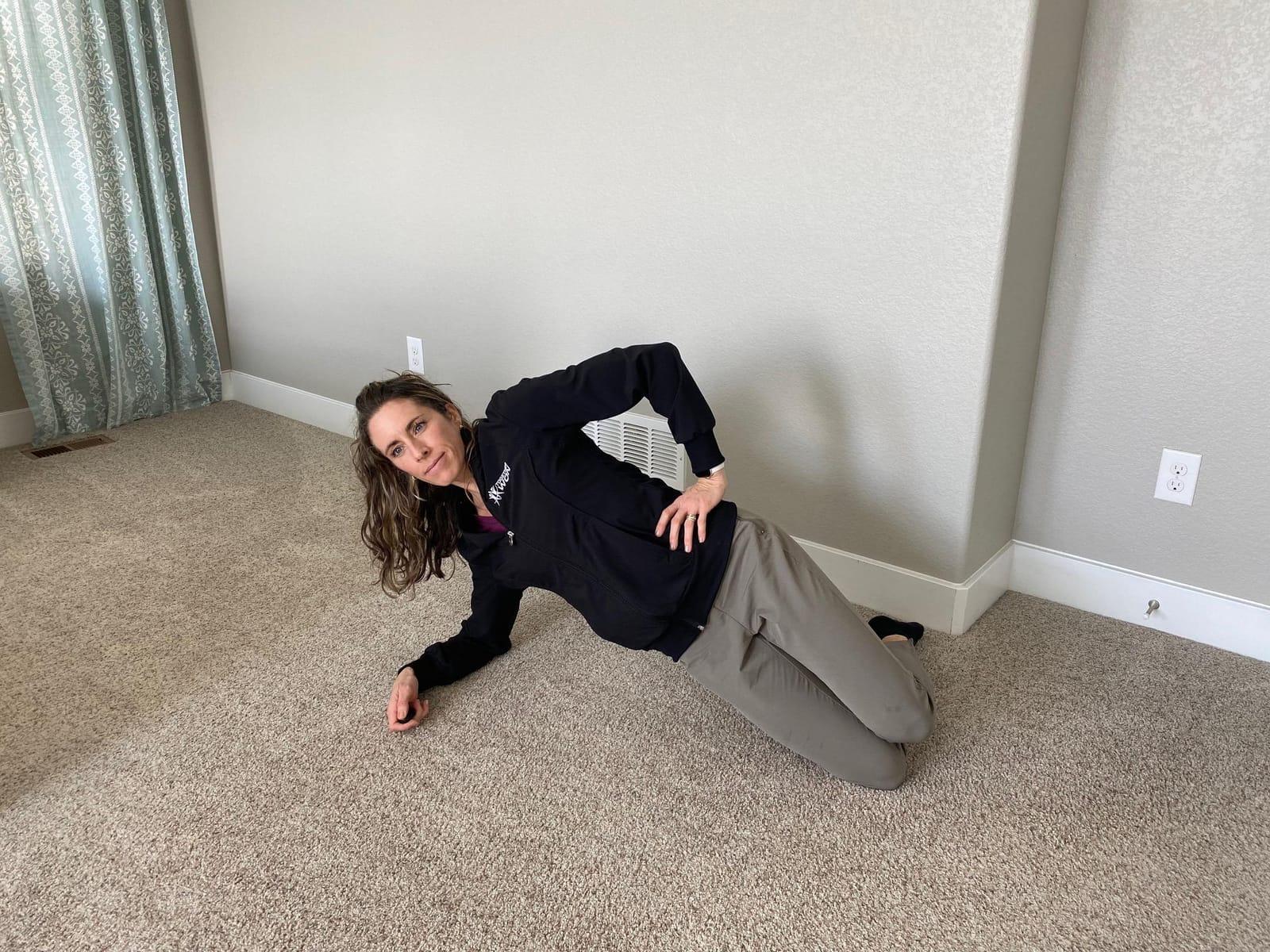 A woman holding a kneeling side plank on her forearm with her hips lifted