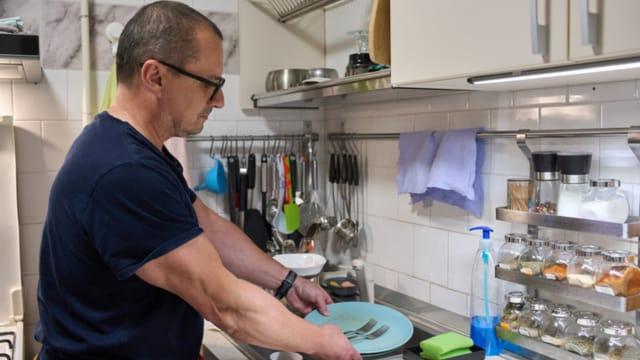 A man standing at a kitchen counter washing dishes