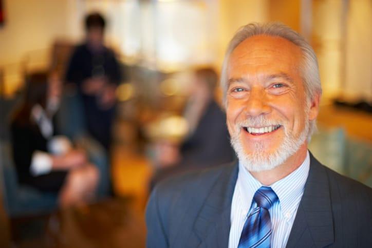 A smiling older man with a white beard in a suit and tie