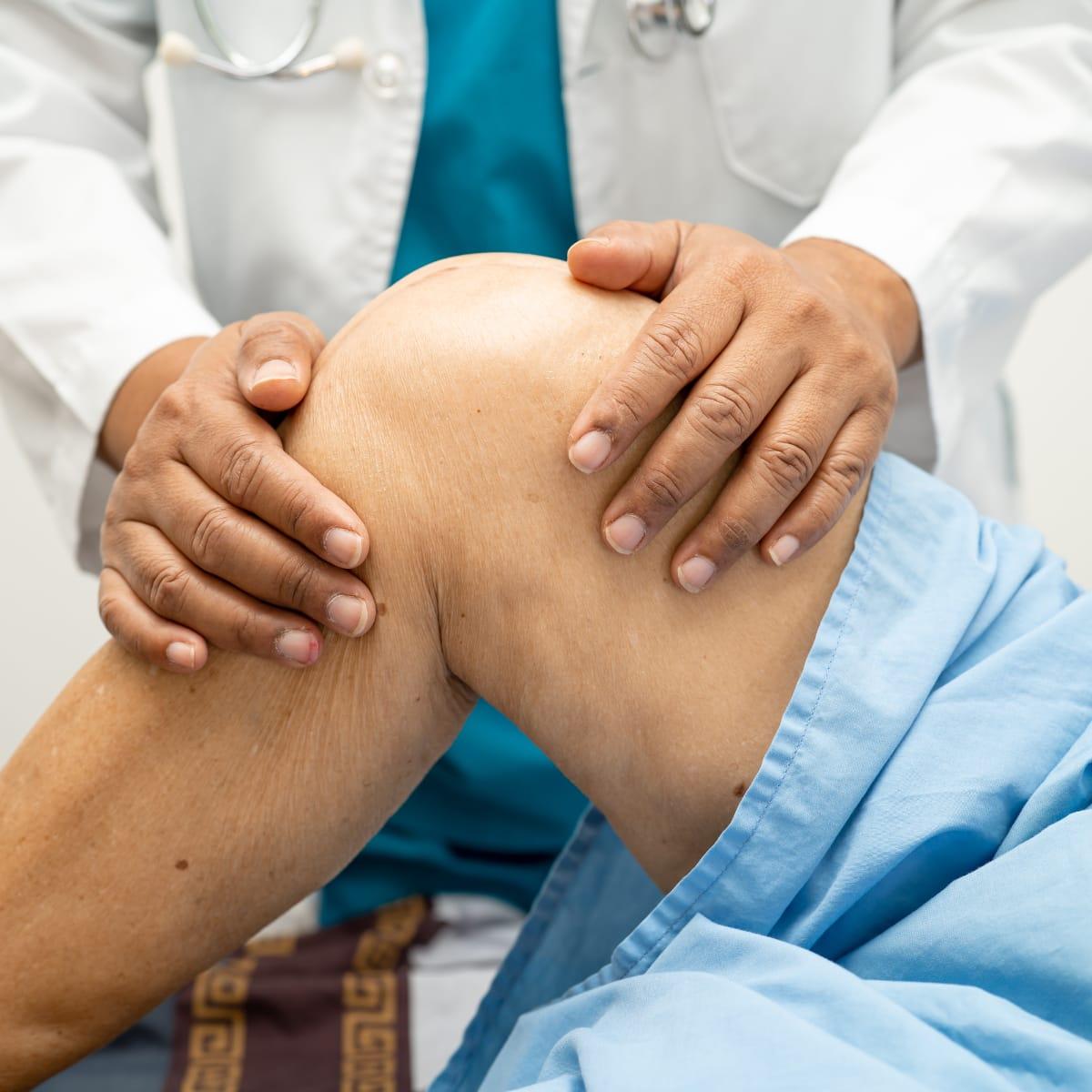 A clinician examining an older woman’s knee