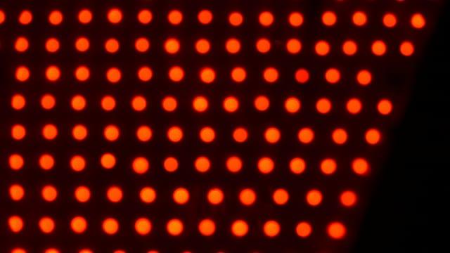 A close-up of rows of glowing red LED lights on a light therapy panel