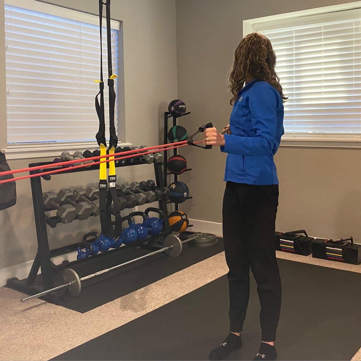 Mid-row from behind, pulling one handle back and turning toward the rowing arm