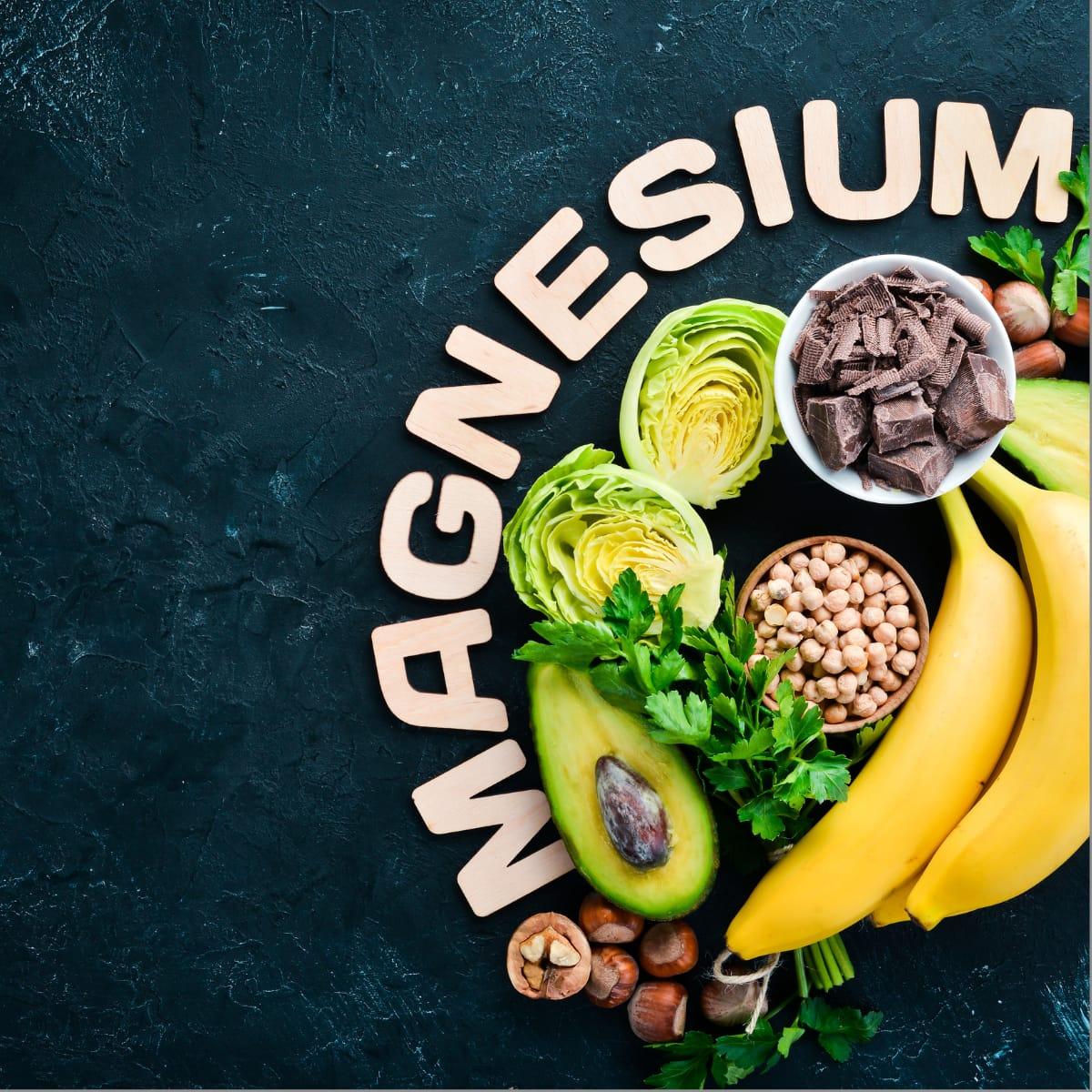 Magnesium-rich foods including avocado, bananas, dark chocolate, chickpeas, hazelnuts and leafy greens arranged beside the word MAGNESIUM