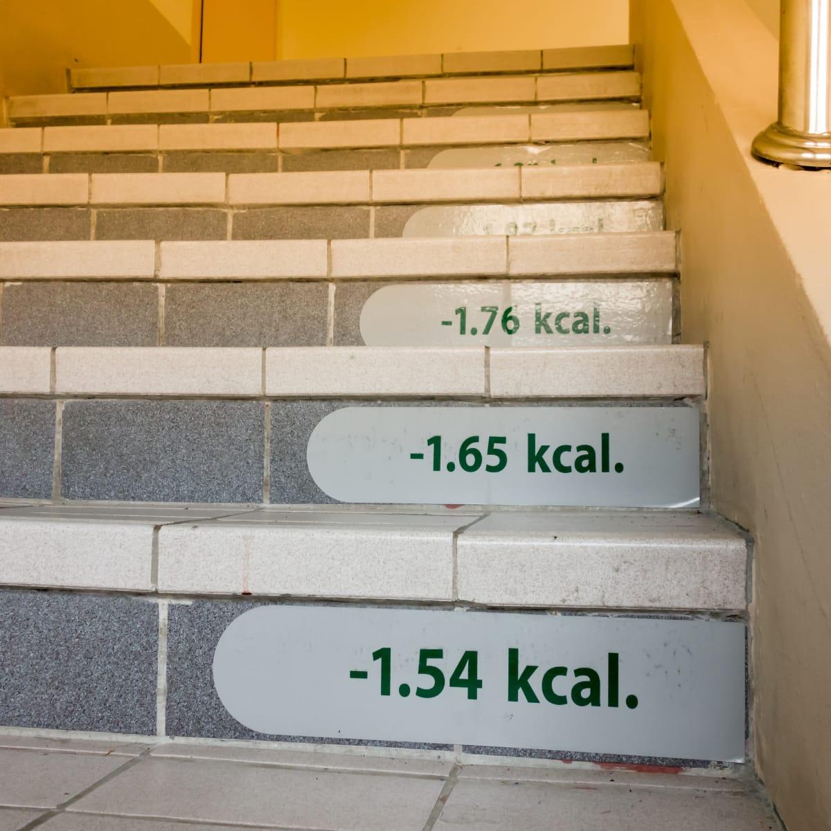 A staircase with calorie counts printed on the risers, such as "-1.54 kcal" and "-1.65 kcal"