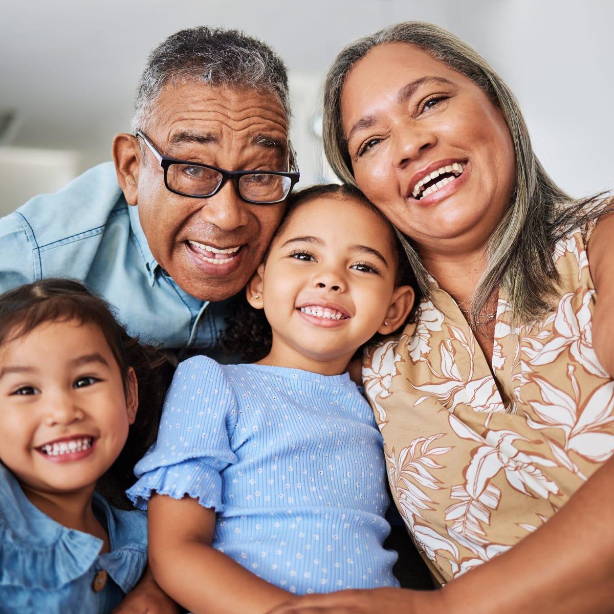 Smiling grandparents cuddled close with their two young granddaughters