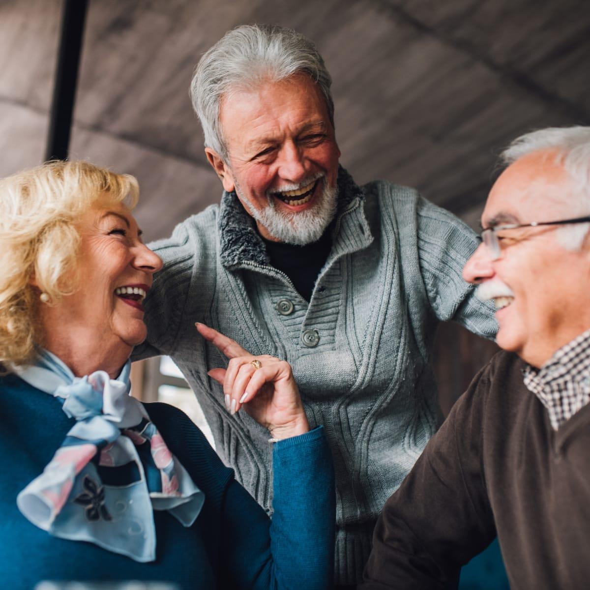 Three older friends laughing together over coffee