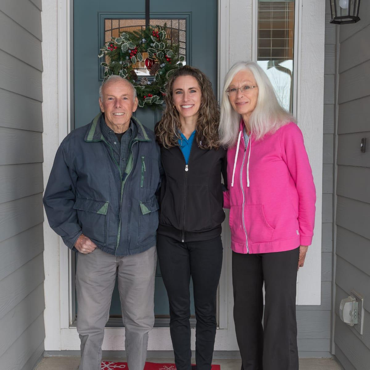 Kristen standing between her mom, Julie, and her dad on a front porch