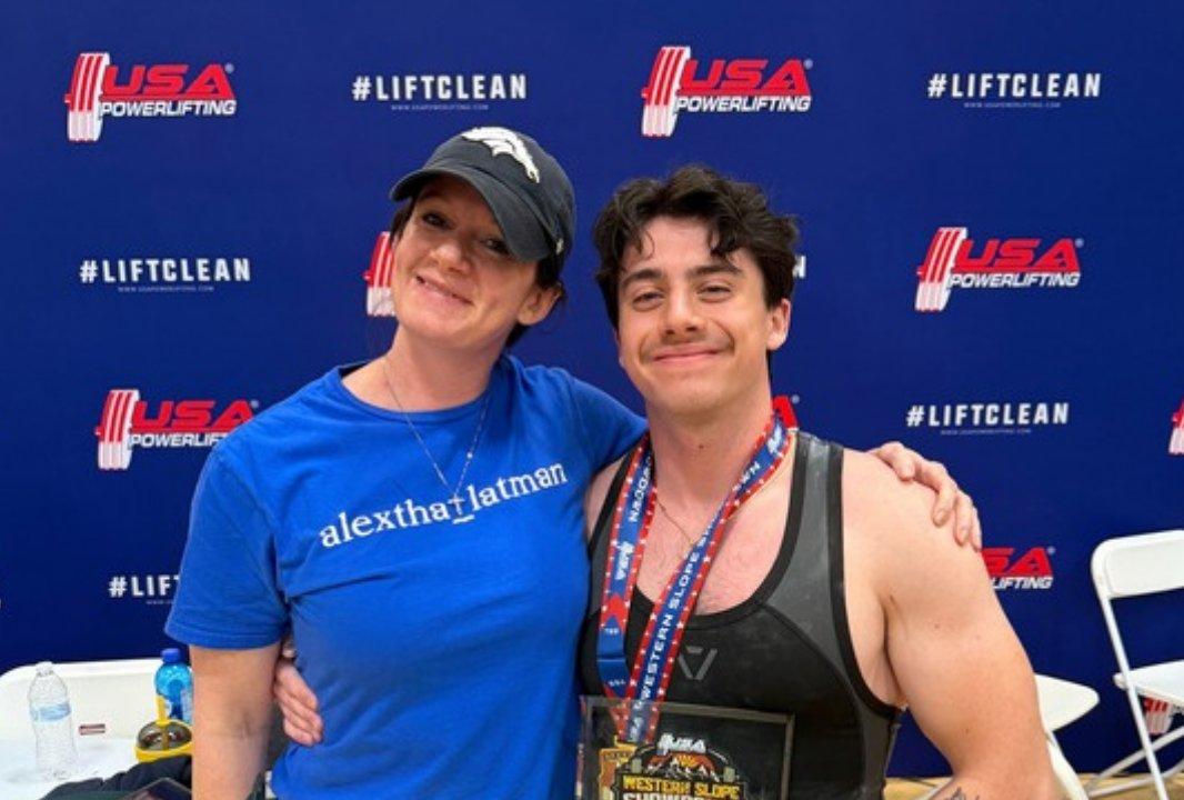 Alex with his arm around his mom at a USA Powerlifting meet, wearing his medal