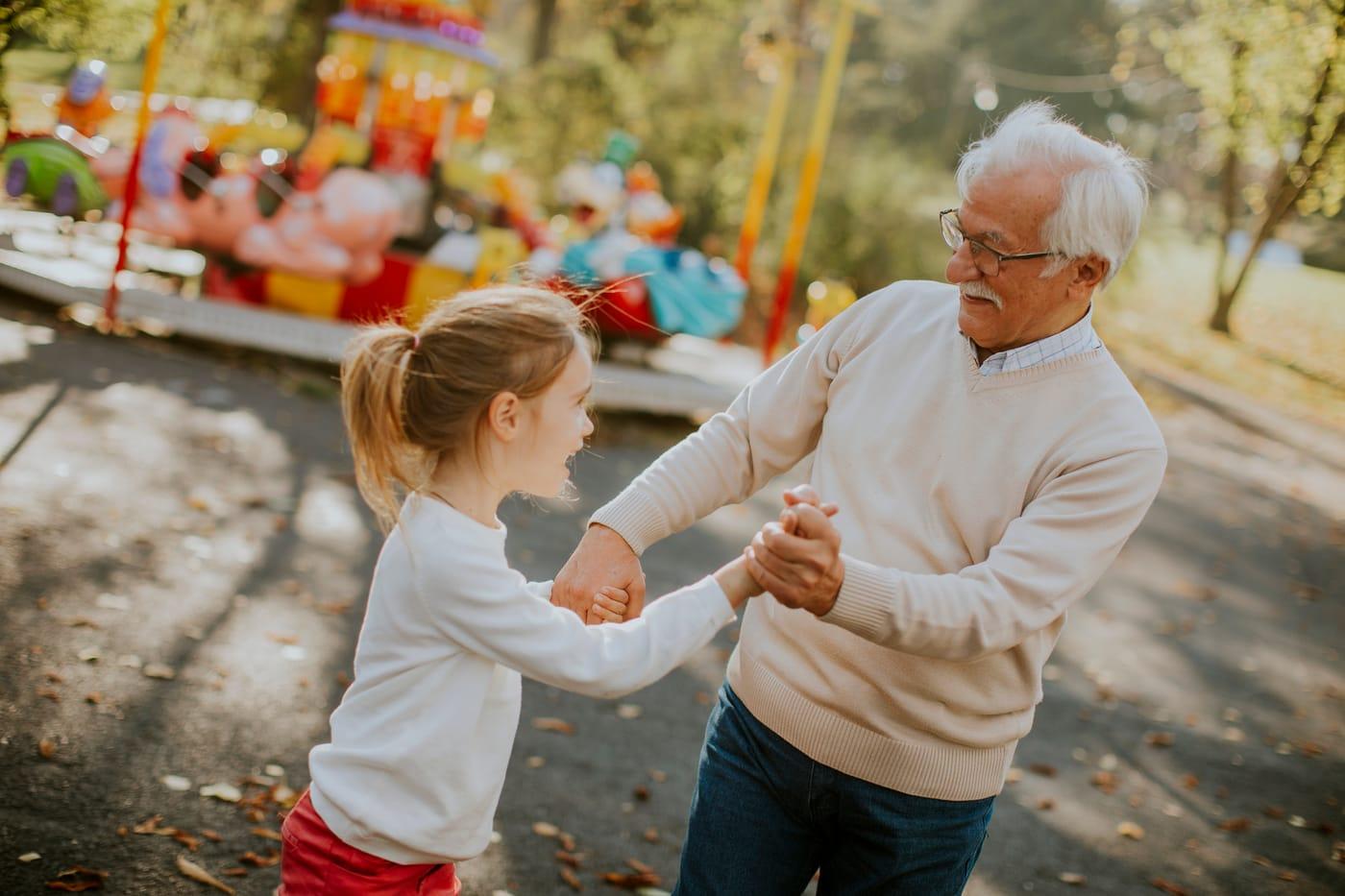 Grandfather holding hands and playing with his granddaughter outdoors