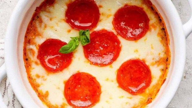 A baked cottage cheese pizza bowl topped with melted mozzarella, pepperoni slices and a basil leaf