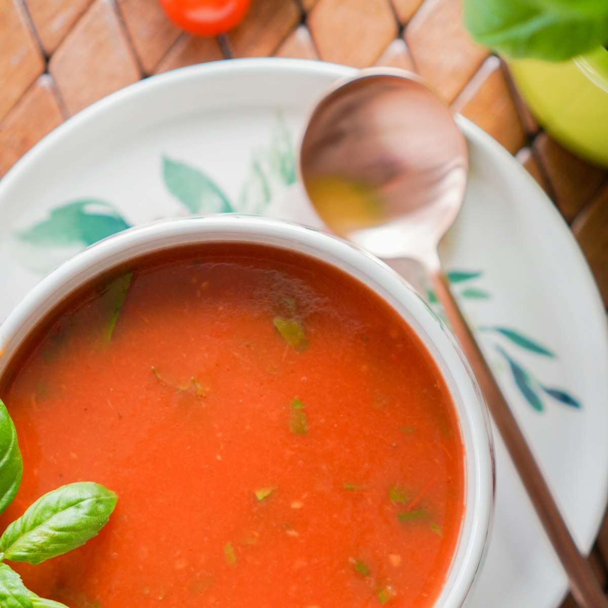 A bowl of smooth tomato soup garnished with fresh basil leaves