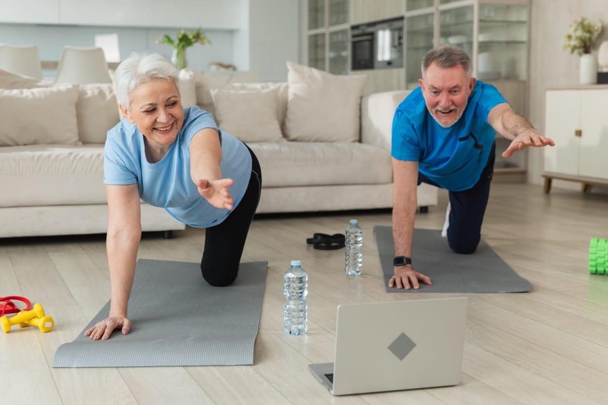 Older couple following an online workout on a laptop at home